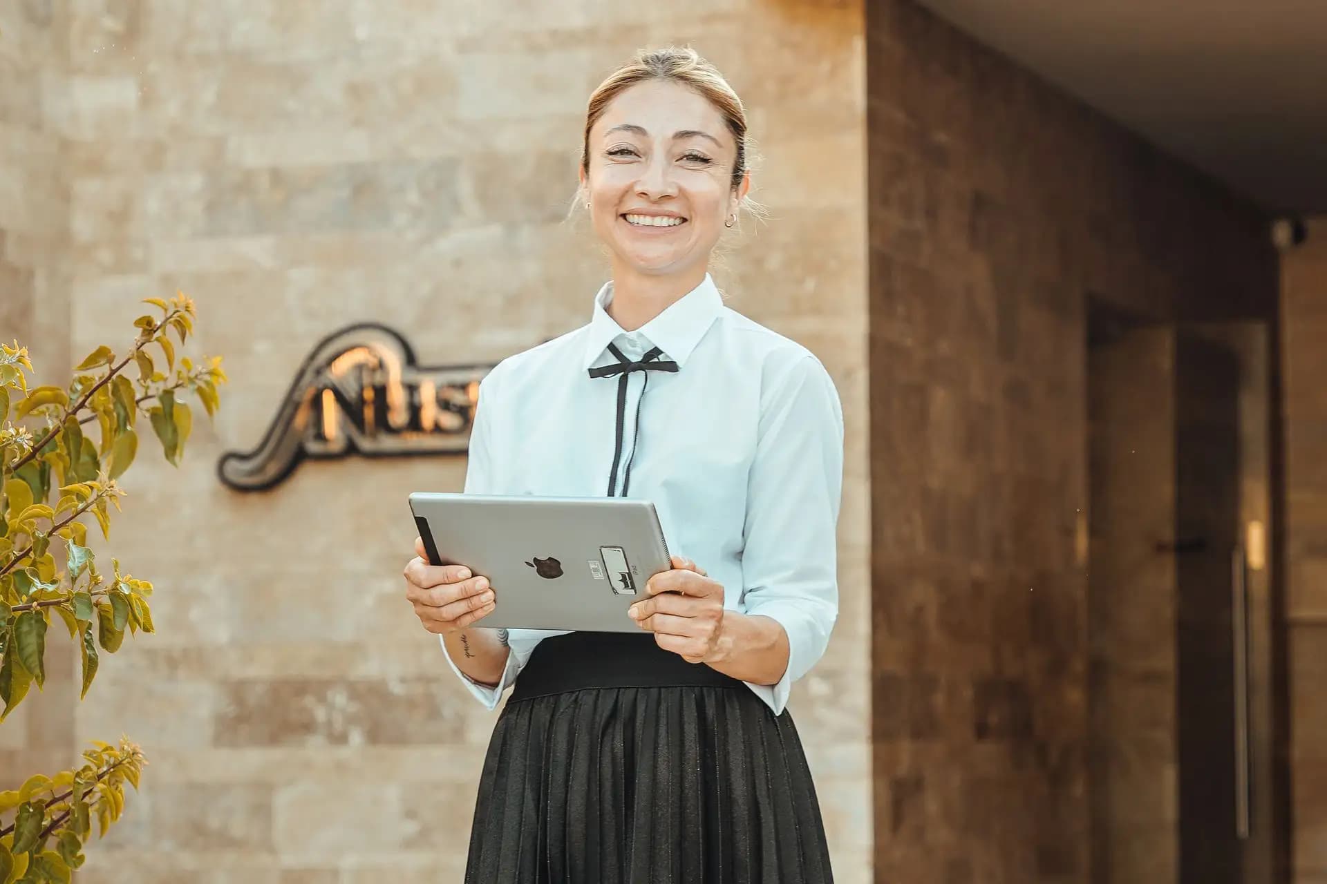 Recepcionista de hotel con una tablet en la entrada, todo el negocio hotelero gestionado desde una sola plataforma con Avirato
